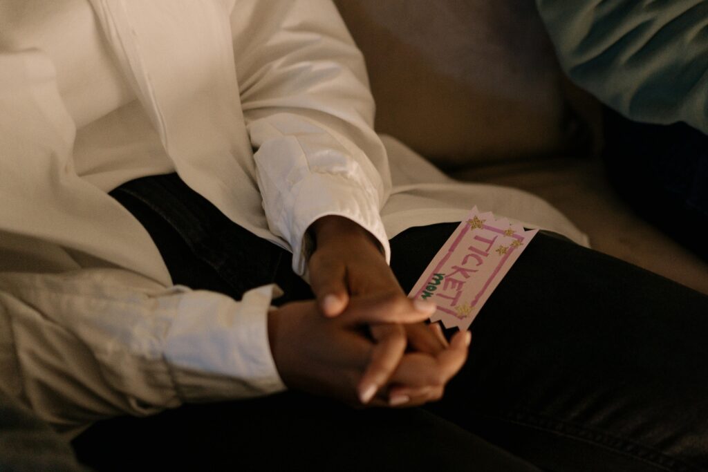 A close-up shot of hands holding a colorful ticket while sitting, conveying anticipation.